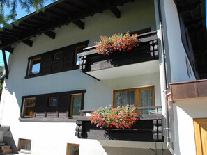 A two-story building with wooden balconies and flower boxes.