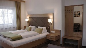 A double bed with two bedside tables, a wooden headboard, a mirror, and a chair. - TAN 1 east (1-2 persons) - Apartments Vilsalp (Bogen)