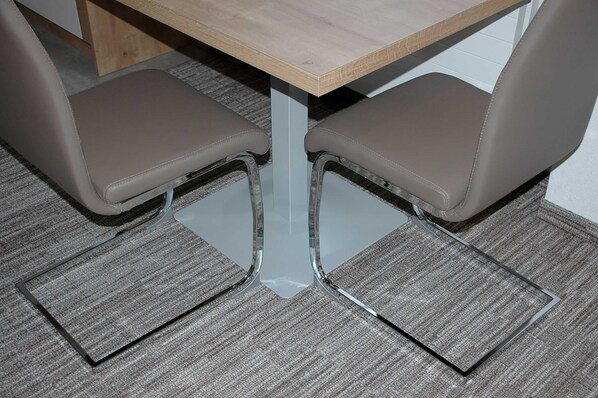 A table with a light wooden top and two chairs with clear plastic legs.