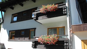 A two-story building with balconies, wooden railings, and flower boxes. - TAN 1 east (1-2 persons) - Apartments Vilsalp (Bogen)
