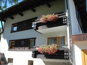 Um edifício de dois andares com varandas, guarda-corpos de madeira e floreiras.