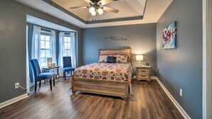 A bedroom with a bed, a ceiling fan, a nightstand, a chair, and a window with curtains. - Suburban Getaway w/ Game Room, 19 Mi to Nashville! (Mt. Juliet)