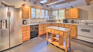 Una cocina moderna con armarios de madera, electrodomésticos de acero inoxidable y ventanas amplias.