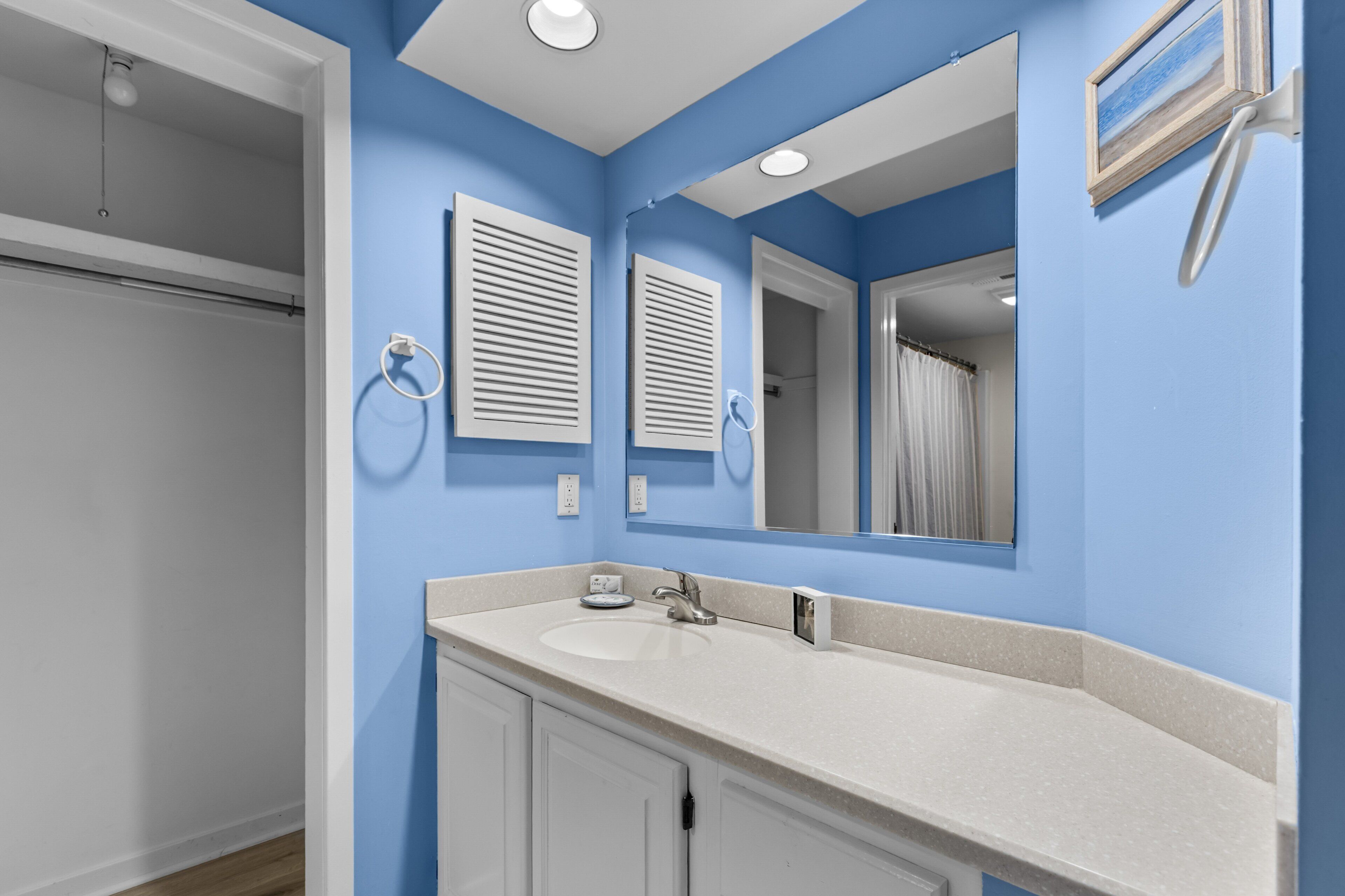 A bathroom with a blue wall, a white sink, and a mirror.