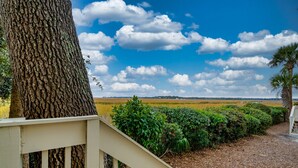 A view from a balcony with a railing, overlooking a field and a clear sky with clouds. - Roomy & Spacious Villa with Great Marsh Views! (Seabrook Island)