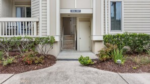 A two-story building with a front entrance, a mailbox, and a small garden area with various plants. - Roomy & Spacious Villa with Great Marsh Views! (Seabrook Island)