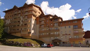 A multi-story hotel with balconies, a parking area, and a sign indicating amenities.