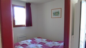 A small bedroom with a single bed, a window with a curtain, and a radiator.