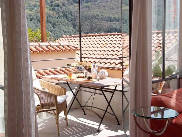 A balcony with a table, chairs, and a glass table.