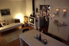 Un salón acogedor con sofá, una mesa de comedor con velas, chimenea y candelabro.