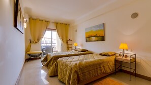 Un dormitorio con dos camas, un escritorio, una silla y un cuadro en la pared.
