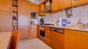 Una cocina moderna con armarios de madera, horno empotrado, microondas y pileta.