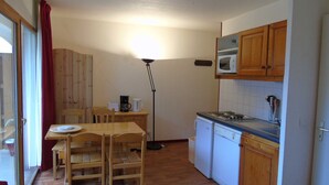 A compact kitchen with wooden cabinets, a microwave, a coffee maker, and a sink.