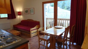 A compact kitchen with a wooden table and chairs, a sofa, and a dining table.