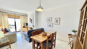 Un comedor con una mesa y sillas de madera, una televisión y un sofá al fondo.