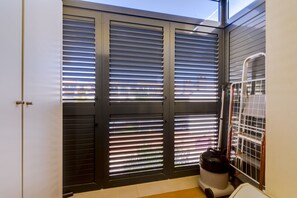 A room with a sliding door with horizontal blinds, a white door, and a small white appliance on the floor. - Paraísos do Pinhal - Vilamoura (Vilamoura)