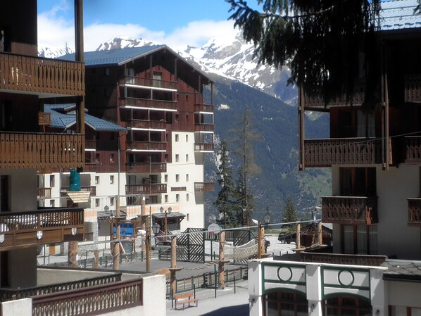 A mountain resort with multi-story buildings, balconies, and a view of snow-capped mountains.