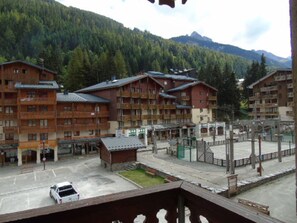 A hotel with multiple wooden buildings, a parking area, and a mountainous backdrop.