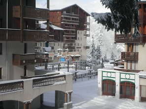 Una località sciistica innevata con edifici a più piani, balconi in legno e un ponte.