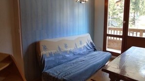 Ein Zimmer mit blauer Wand, einer Holzbank und einem Tisch mit Kunststoffabdeckung.