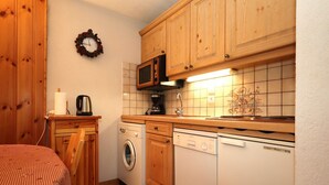 A compact kitchen with wooden cabinets, a microwave, a washing machine, and a dishwasher. - 2-room cabin apartment in Les Houches, balcony, sleeps 4 (Les Houches)