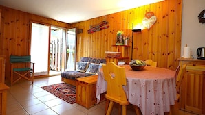 A cozy wooden interior with a dining table, chairs, a sofa, and a small kitchen area. - 2-room cabin apartment in Les Houches, balcony, sleeps 4 (Les Houches)