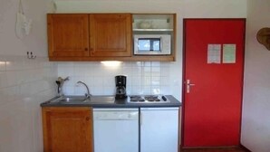 A compact kitchen with wooden cabinets, a microwave, a coffee maker, and a dishwasher. - Valfréjus: 2-room apartment, near ski lift, pet-friendly (Valfréjus)