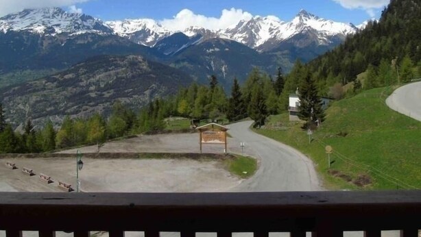A mountainous landscape with snow-capped peaks, a winding road, and a small wooden structure in the foreground. - Valfréjus: 2-room apartment, near ski lift, pet-friendly (Valfréjus)
