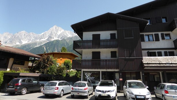 Un bâtiment doté d’un balcon, avec une montagne en arrière-plan.