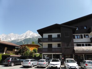 Ein Gebäude mit einem Balkon und einem Berg im Hintergrund.