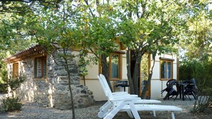 A stone building with a tiled roof, a small tree, and outdoor seating with white chairs and a table. - La Petite Bergerie - pure nature! Vacation home in unspoiled nature. (Termes)