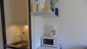 Et lille tekøkken med komfur, vask, mikroovn og minikøleskab.