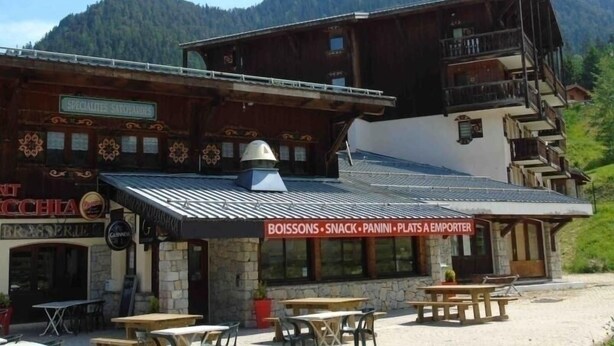 Et rustikt fjeldhotel med et skilt der viser 'BOISSONS, SNACK, PANINI, PLATS A EMPORTER'.
