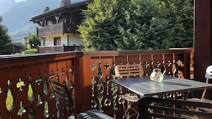A balcony with a table and chairs, overlooking a mountain landscape.