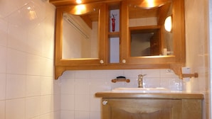 A bathroom with a wooden vanity, a white bathtub, and a mirror above the sink.