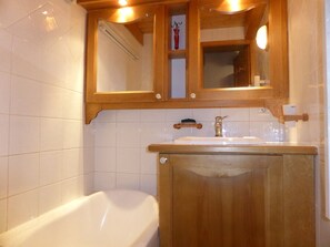 Une salle de bain avec un meuble-lavabo en bois, une baignoire blanche et un miroir au-dessus du lavabo.