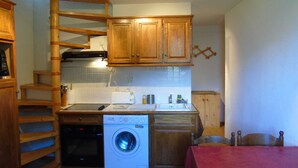 A compact kitchen with wooden cabinets, a built-in washing machine, a toaster, and a sink. - Cozy 2-Room Mezzanine Apartment for 4, Steps from Lift & Shops in Valfréjus (Valfréjus)