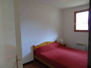 Cozy retreat with a wooden bed, bedside table, and window.