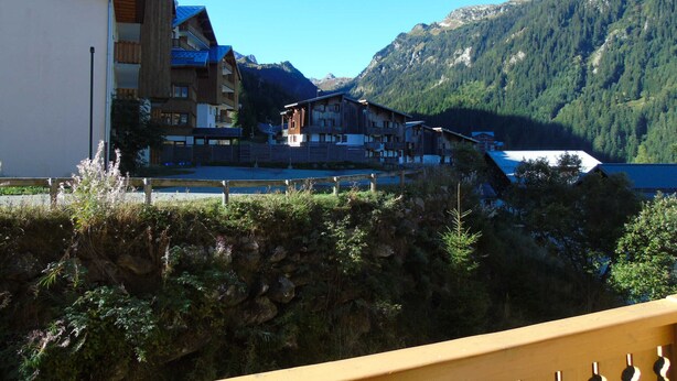 A mountain resort with wooden buildings, a clear sky, and a view of the mountains. - Cozy 2-Room Apartment - Ski-In/Ski-Out, Balcony, Pet-Friendly, Sleeps 6 (Valfréjus)