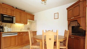 Una cocina con armarios de madera, microondas, tostadora y una mesa de comedor con sillas.