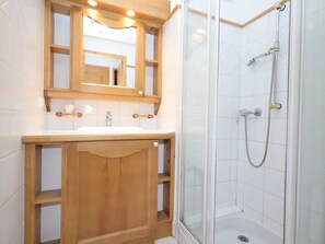 A bathroom with a wooden vanity, a mirror, a shower with a glass door, and white tiled walls. - 2-room cabin apartment, pool, pets allowed, near cable cars (Les Houches)