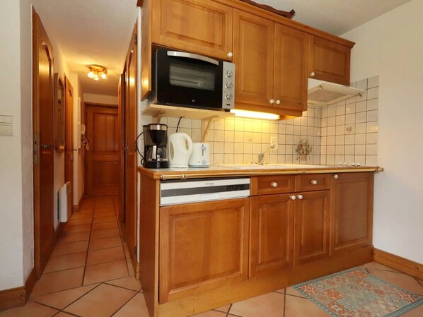 Eine Küche mit Holzausstattung, einer Mikrowelle, einer Kaffeemaschine, einem Toaster und einem Geschirrspüler.