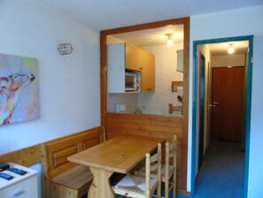 Una stanza piccola e accogliente con un tavolo e una panca di legno, un forno a microonde e una porta che dà su un'altra stanza.