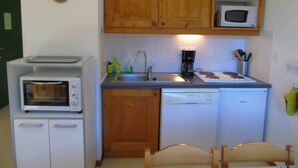 A compact kitchen with wooden cabinets, a microwave, a toaster, a sink, and a dishwasher. - Cozy apartment, pets welcome - 6 guests (Valfréjus)