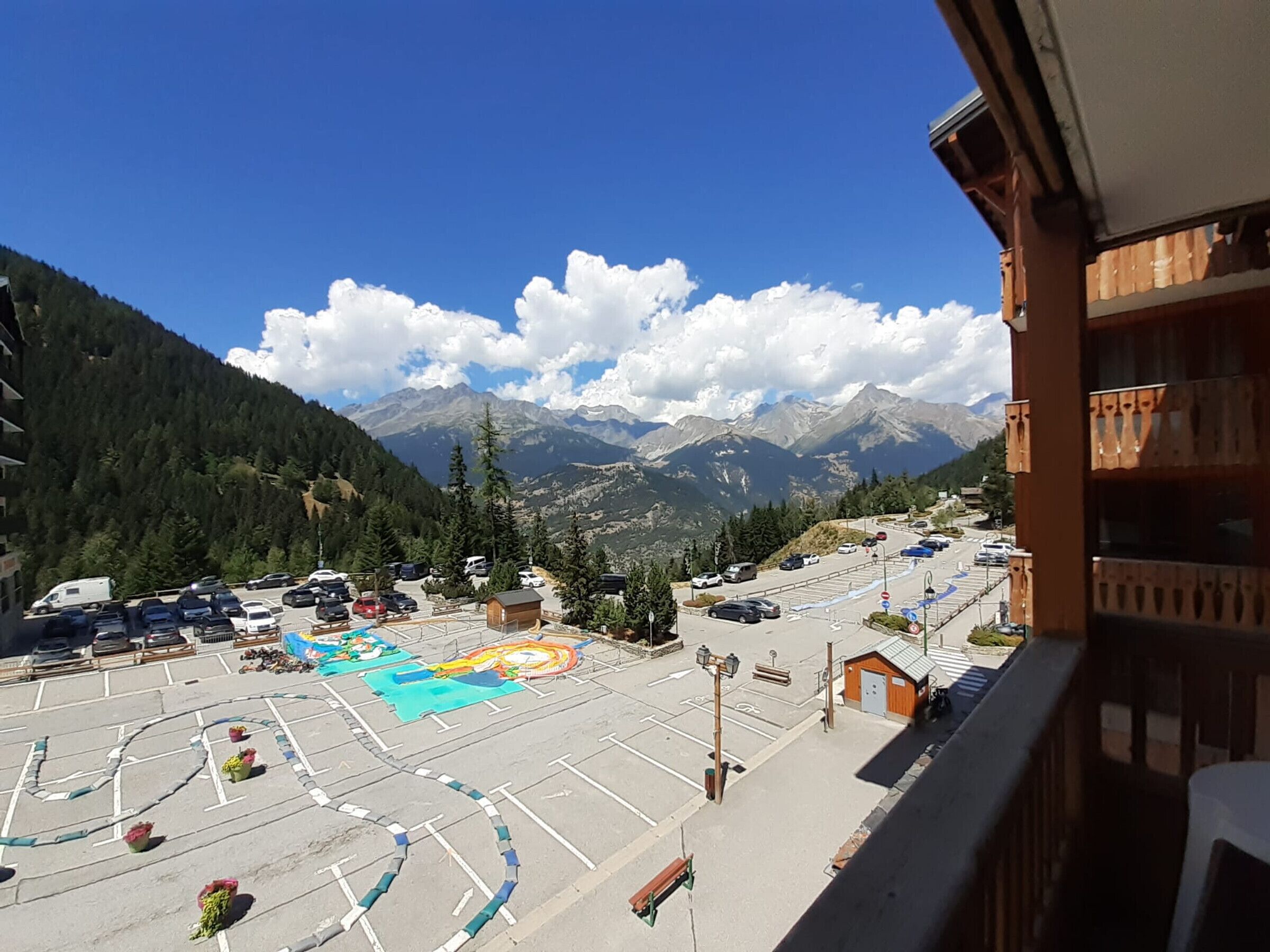 A parking area with vehicles, a small building, and a mountain view.