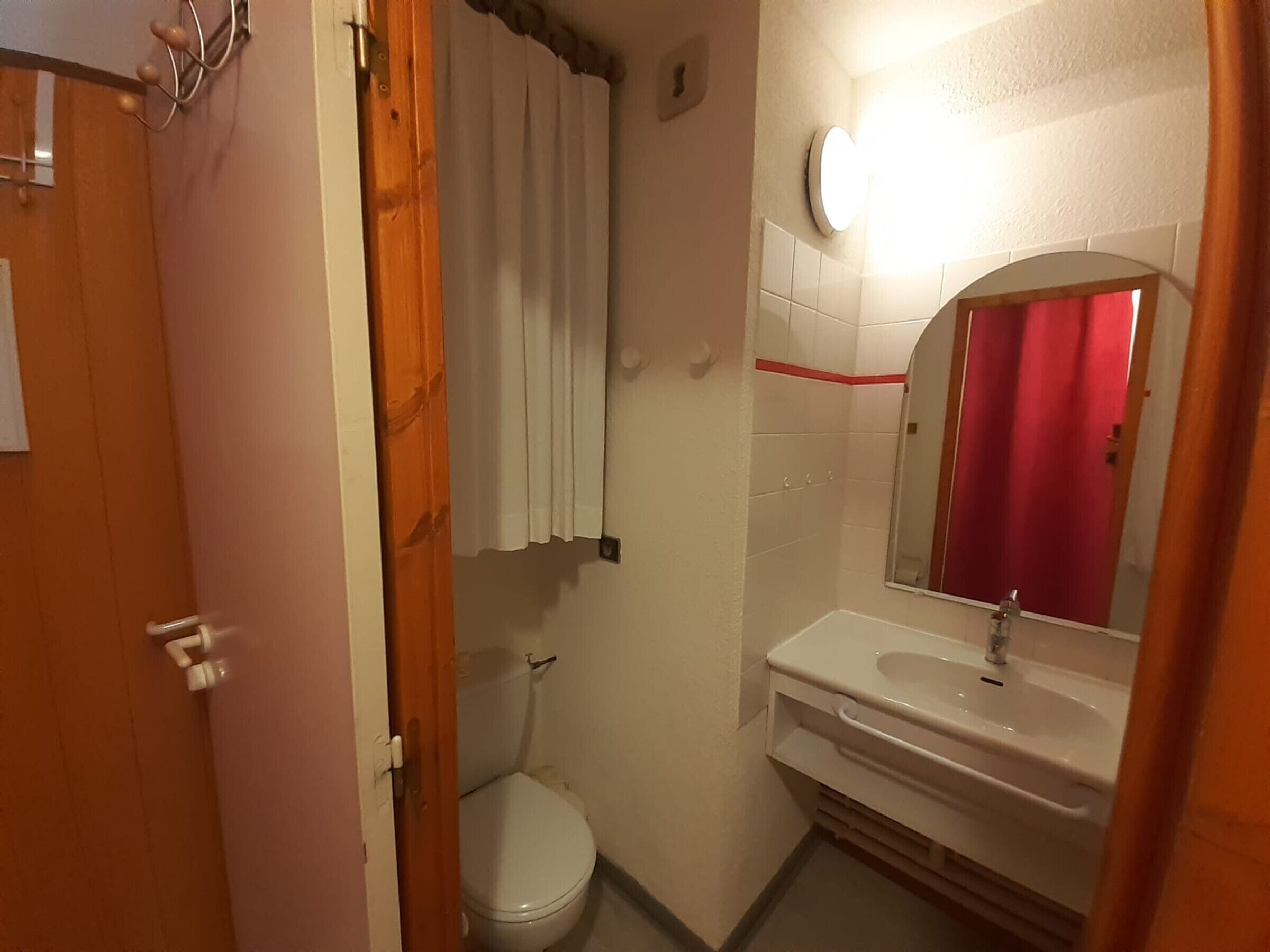 A bathroom with a toilet, sink, and mirror.