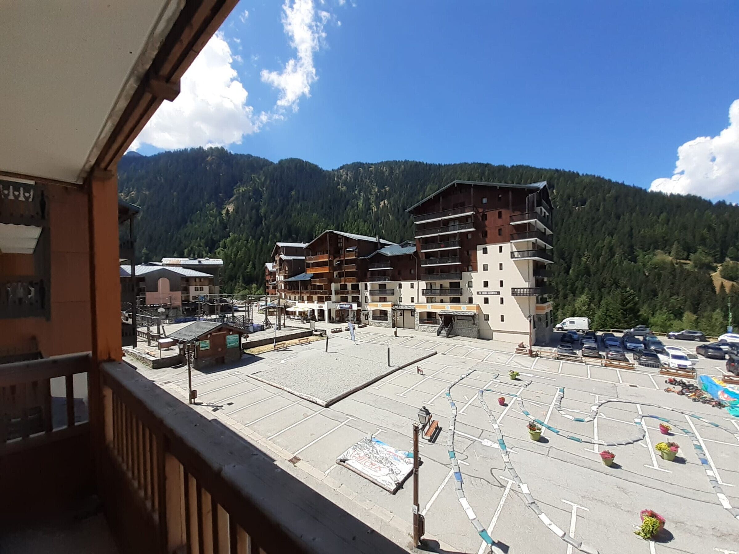 A hotel with multiple floors, outdoor parking, and a mountainous backdrop.