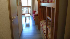 A narrow hallway with a wooden staircase leading to a room with bunk beds and a small table. - Cozy Studio for 4 near Ski Lifts and Shops, Includes Linens, Kitchen, Balcony with Scenic Views (Valfréjus)