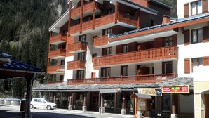 Ein mehrstöckiges Hotel mit Balkonen, einem Hinweisschild für einen Skigebiet und einer Fotostation.