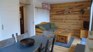 Un salon chaleureux avec un mur en bois, un canapé, une table à manger avec des chaises et un petit meuble en bois.